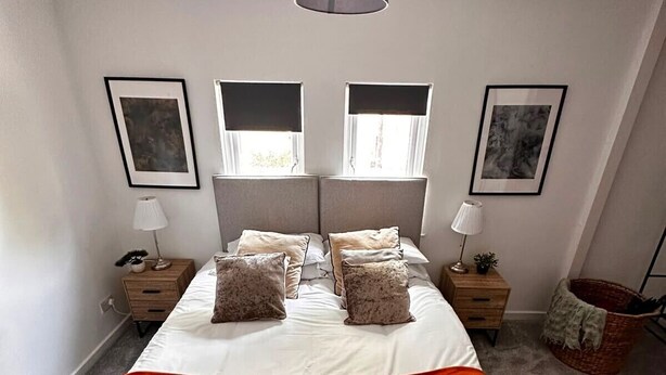 A neatly arranged bedroom with a bed, bedside tables, lamps, and artwork on the walls. - House Sleeps 4 with Patio (Warwick)
