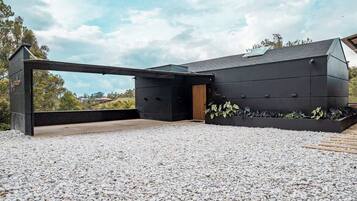 Um edifício moderno com telhado plano, grande beirada e entrada com calçamento de cascalho.