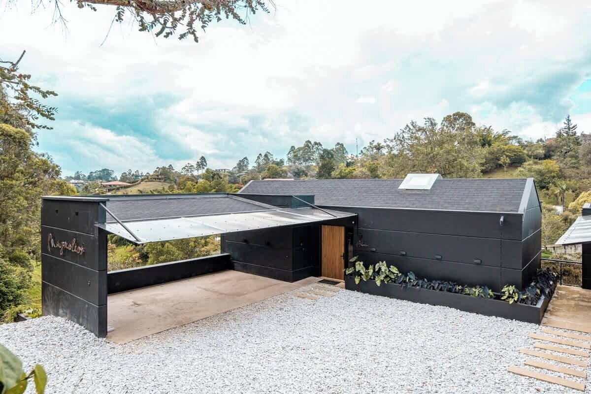 A modern building with a flat roof, a covered outdoor area, and a gravel ground.