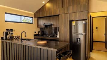 A modern kitchen with a central island, stainless steel appliances, and a view of the outdoors.
