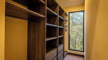 A hallway with built-in wooden shelving units and a window with a view of trees.