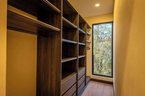 A hallway with built-in wooden shelving units and a window with a view of trees.