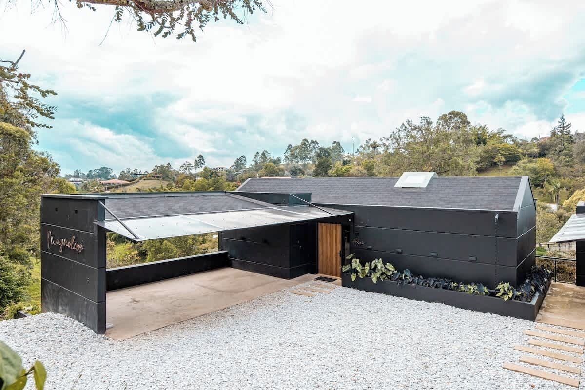 Um edifício moderno com telhado plano, área externa coberta e piso de cascalho.