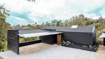 Um edifício moderno com telhado plano, área externa coberta e piso de cascalho.