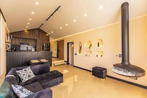 Ein modernes Wohnzimmer mit einer Couch, einem Kamin und einer Küche im Hintergrund.