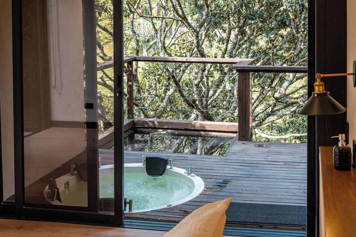 A wooden deck with a hot tub and a view of trees.