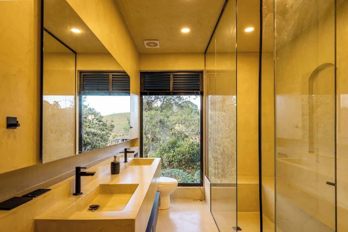 Uma casa de banho moderna com um espelho grande, uma pia e uma sanita.