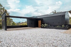 A modern building with a flat roof, a large overhang, and a gravel driveway.