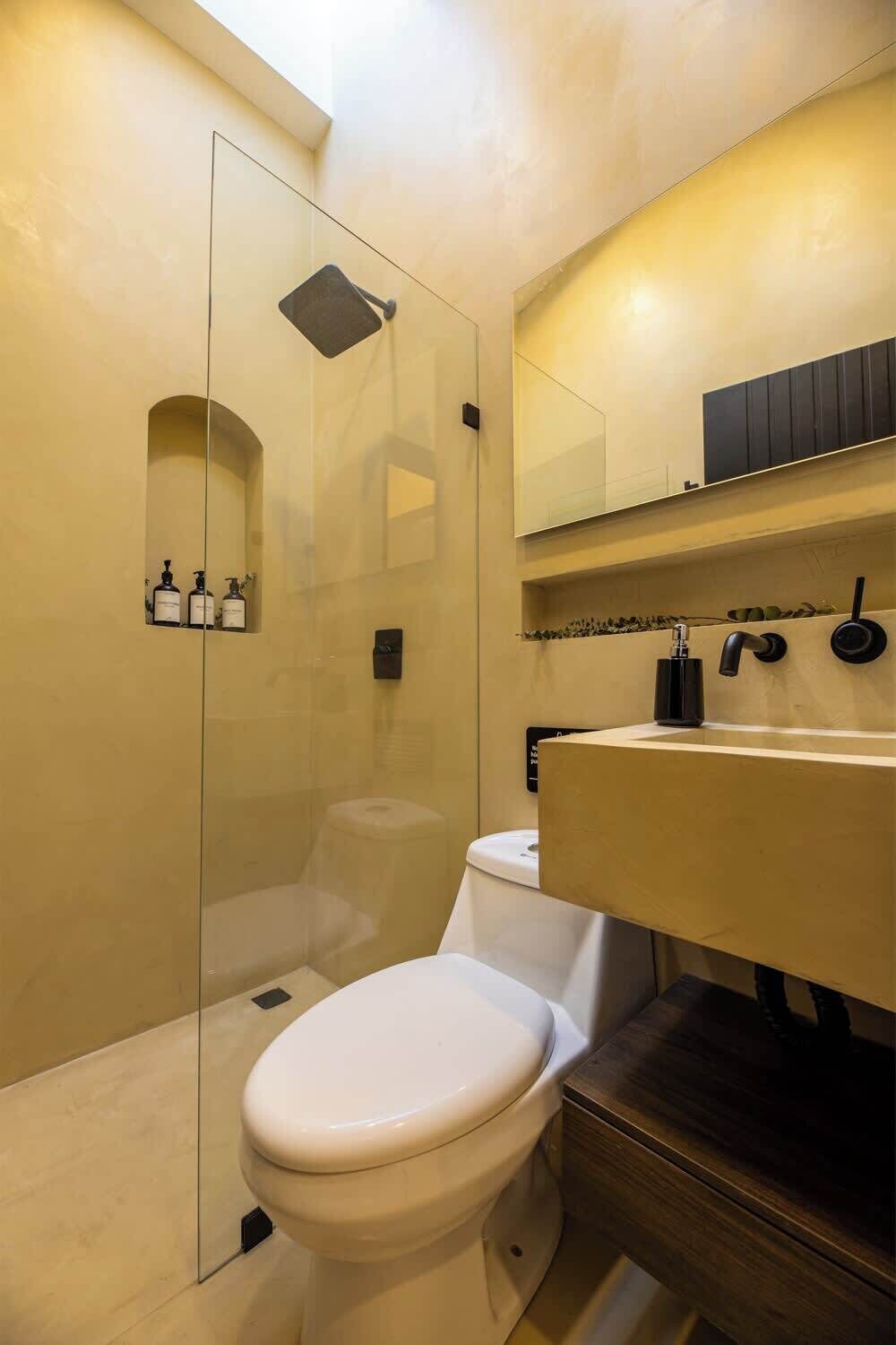 A bathroom with a glass-enclosed shower, a white toilet, and a vanity with a mirror and towel rack.