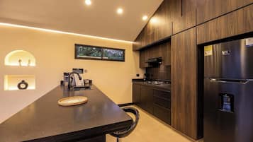 Una cocina moderna con encimera oscura, armarios de madera y un refrigerador de acero inoxidable.
