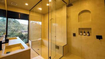Un baño moderno con cabina de ducha acristalada, un ventanal grande y un lavabo con espejo.