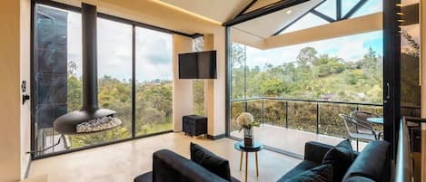 A modern living room with a large sofa, a flat-screen TV, and a fireplace.