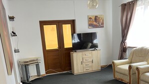 A living room with a television, a sofa, a table with a decorative item, and a door with a window.