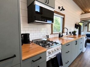 Una cocina moderna con estufa a gas, encimera de madera y armarios grises.