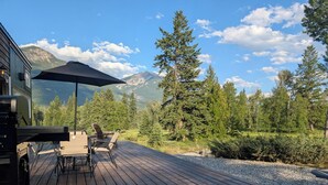 A wooden deck with outdoor furniture, a grill, and a mountain backdrop. - Nicholson Tiny Home with Hot Tub & Mountain Views (Golden)