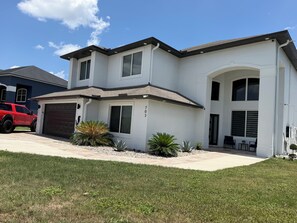 A two-story house with a garage, a driveway, and a well-maintained lawn. - Luxurious modern estate minutes from Disney (Davenport)
