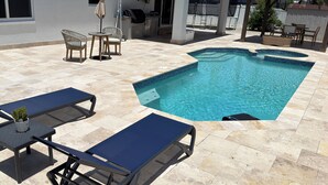 Ein Schwimmbad mit Liegestühlen und einer überdachten Terrasse.