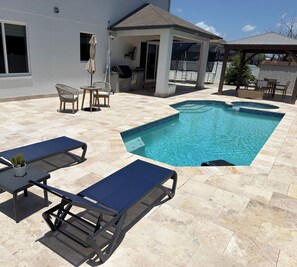 A swimming pool with lounge chairs and a covered patio area. - Luxurious modern estate minutes from Disney (Davenport)