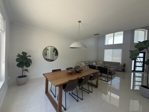 A modern living room with a dining area, a sofa set, and large windows. - Luxurious modern estate minutes from Disney (Davenport)