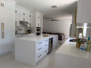 A modern kitchen with white cabinetry, a central island, stainless steel appliances, and a ceiling fan. - Luxurious modern estate minutes from Disney (Davenport)