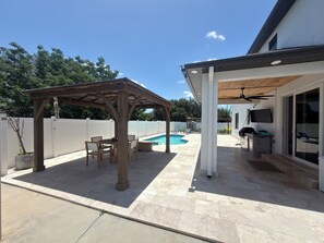 A covered patio area with a pool, outdoor seating, and a grill. - Luxurious modern estate minutes from Disney (Davenport)