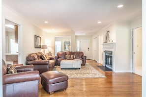 A spacious living room with leather sofas, a fireplace, and a large mirror. - The Fairway Retreat on Pinehurst #5! (Pinehurst)