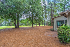 A residential property with a covered patio, a lawn, and a wooded area. - The Fairway Retreat on Pinehurst #5! (Pinehurst)