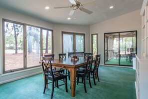 Ein Esszimmer mit großem Tisch, Stühlen und Deckenventilator.