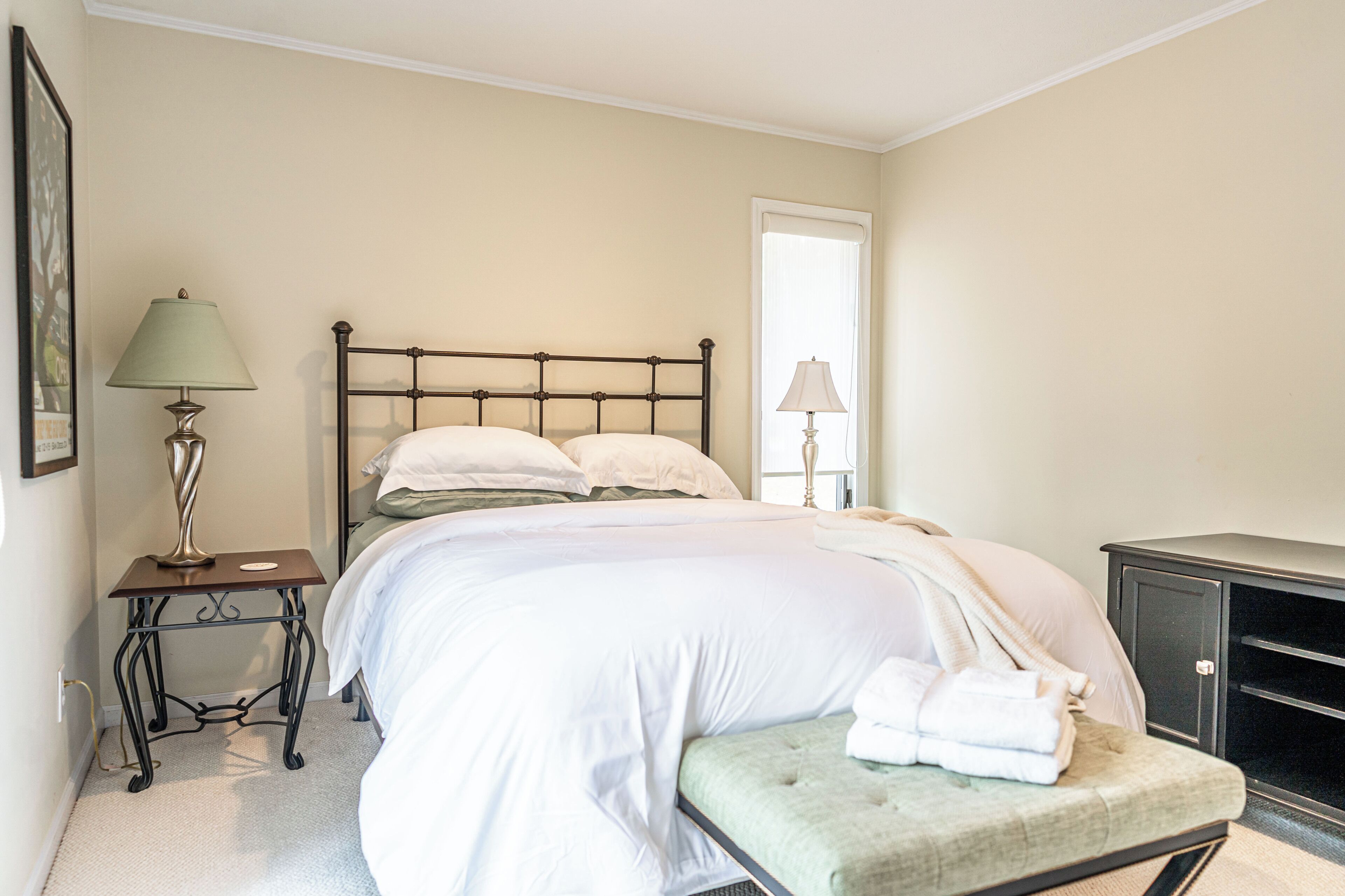 Une chambre à coucher comprenant un lit, des tables de chevet, un banc et une armoire.