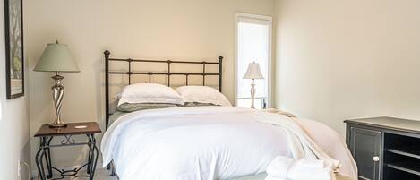 Une chambre à coucher comprenant un lit, des tables de chevet, un banc et une armoire.