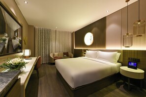 A modern hotel room with a large bed, a desk, a chair, a round mirror, and a bedside table with a digital clock. - Crystal Orange Guomao Joy City (Beijing)