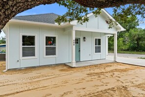 A two-story building with a covered porch, a visible door number, and a tree in the foreground. - Fall Deals + Snowbird Rates | Near Downtown & Historic St. Andrews Bay (Panama City)