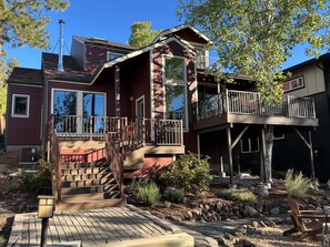 A two-story house with a balcony, a staircase, and a garden area. - Tree house steps from the river (Bend)