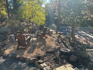 A garden area with outdoor seating, a fire pit, and a paved path. - Tree house steps from the river (Bend)