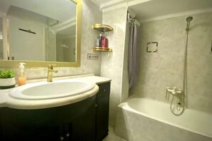 A bathroom with a sink, mirror, shower, and bathtub. - Bright City Flat Close to Acropolis Museum (Athens)