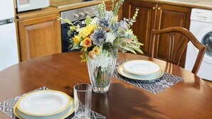 A dining table with a vase of flowers, plates, and a glass of water. - Bright City Flat Close to Acropolis Museum (Athens)