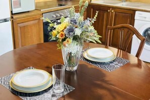 A dining table with a vase of flowers, plates, and a glass of water. - Bright City Flat Close to Acropolis Museum (Athens)
