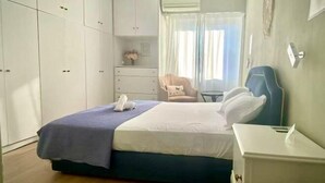 A hotel room with a bed, a bedside table, a chair, a wardrobe, and a window with curtains. - Bright City Flat Close to Acropolis Museum (Athens)