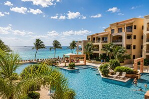 A resort with multiple swimming pools, palm trees, and a view of the ocean. - Luxury Oceanfront 3BR Condo with Huge Terrace, Private Plunge Pool & Ocean Views (Playa del Carmen)