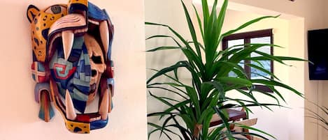 Een kamer met een decoratief object aan de muur en een potplant.