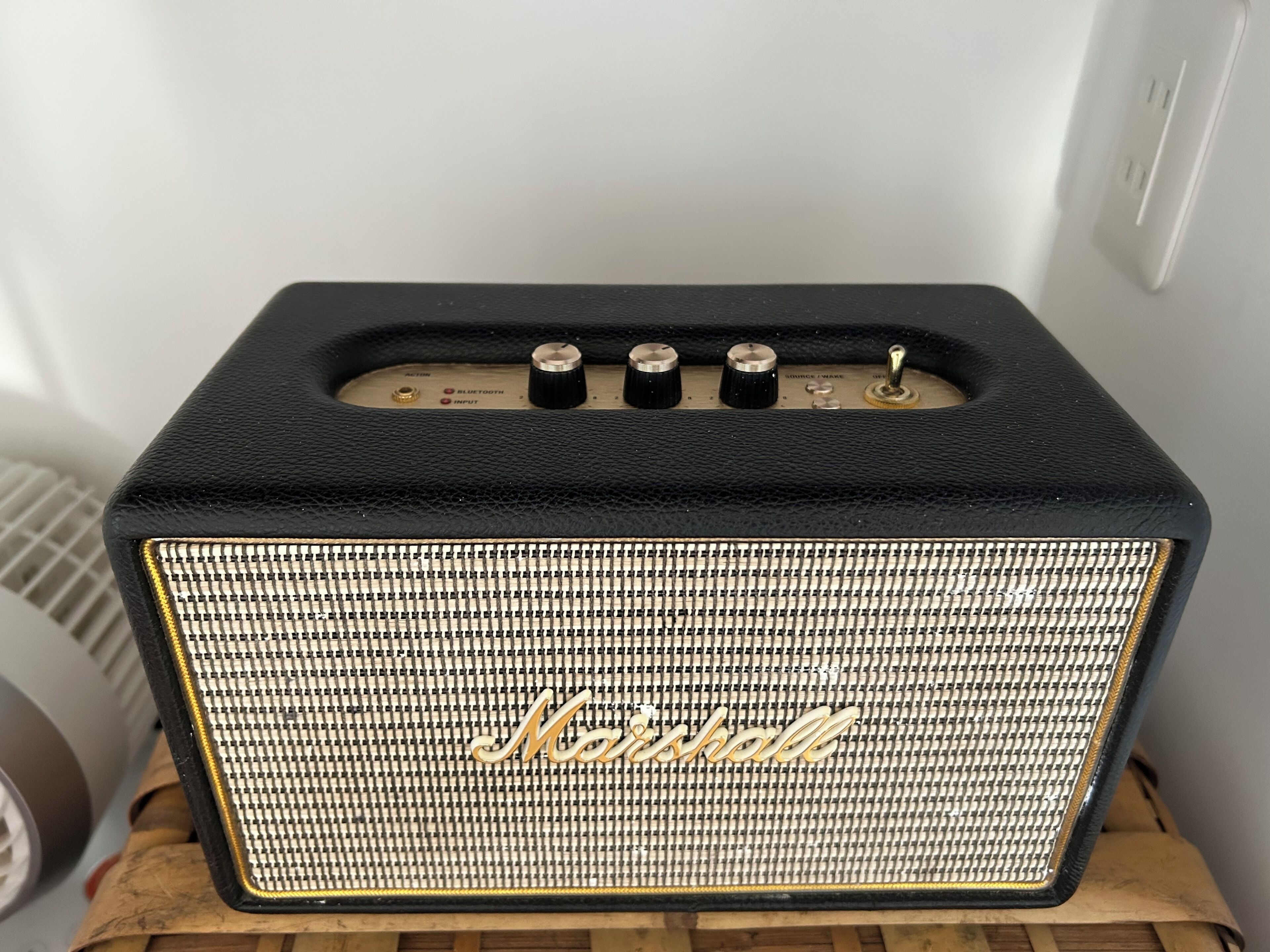 Een Marshall-versterker met een zwart en goud ontwerp, met een speakerrooster en bedieningsknoppen.