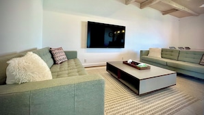A modern living room with two sofas, a coffee table, and a flat-screen TV mounted on the wall. - Zeni House (Otaru City)