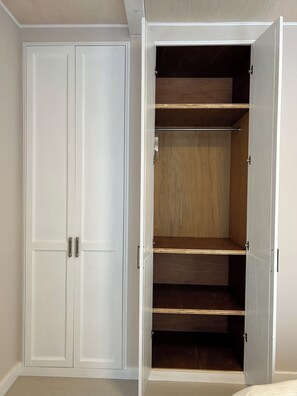 A room with a closed white door and an open closet with wooden shelves.