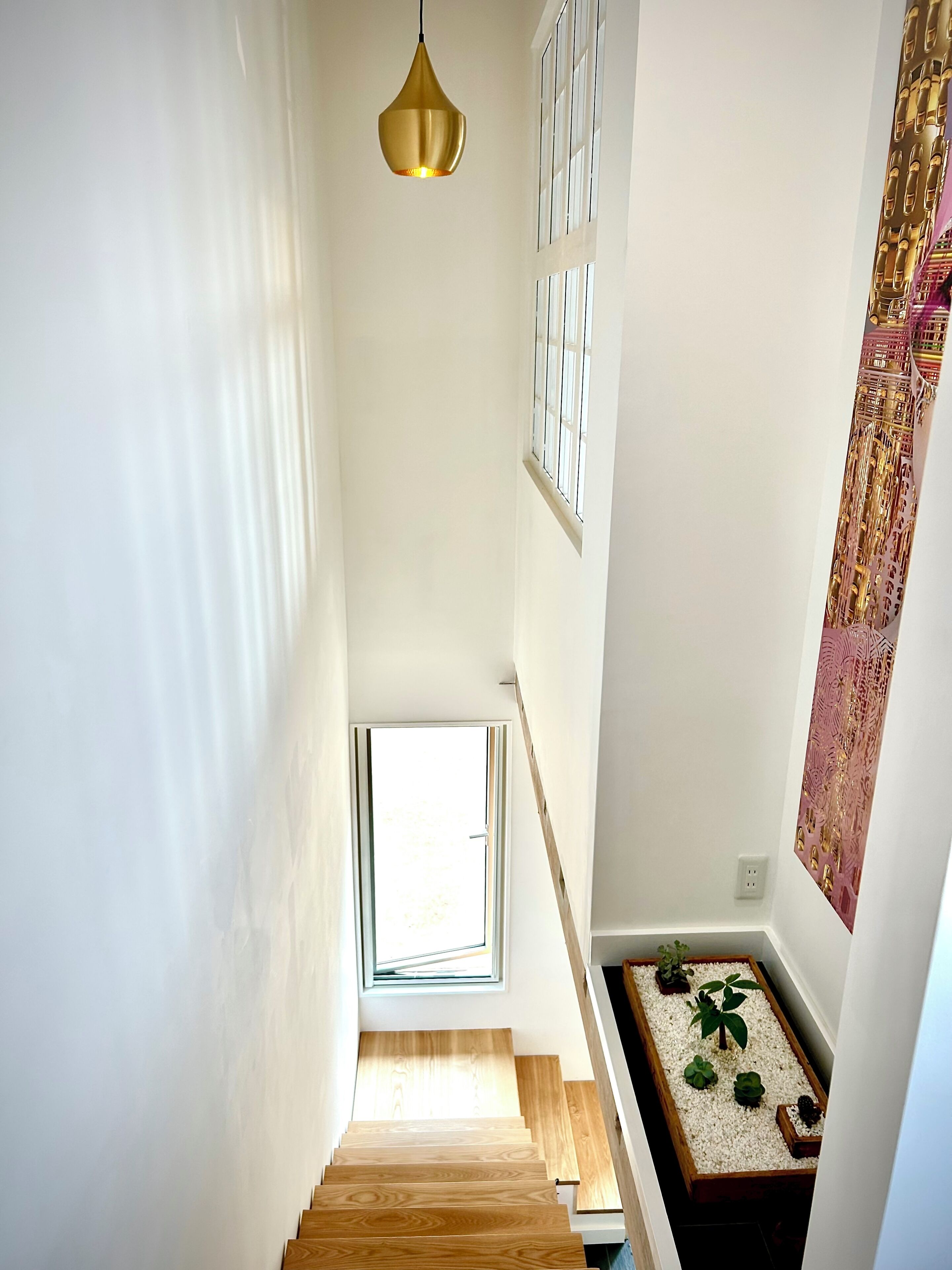 Una escalera de madera conduce a un rellano con un ventanal pequeño.