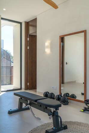 Ein modernes Fitnessstudio mit einer Bank, Kurzhanteln und einem großen Spiegel.