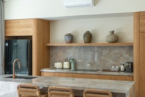 Eine moderne Küche mit Marmorarbeitsplatte, Holzschränken und einer eingebauten Ablage mit dekorativen Vasen.