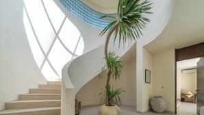 A modern interior with a spiral staircase, a large potted plant, and a minimalist design. - NAVA - Contemporary 3BR Villa (Badung)