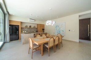 Eine moderne Küche mit einer zentralen Kochinsel, einem Essbereich mit Holztisch und -stühlen sowie einem großen abstrakten Gemälde an der Wand.