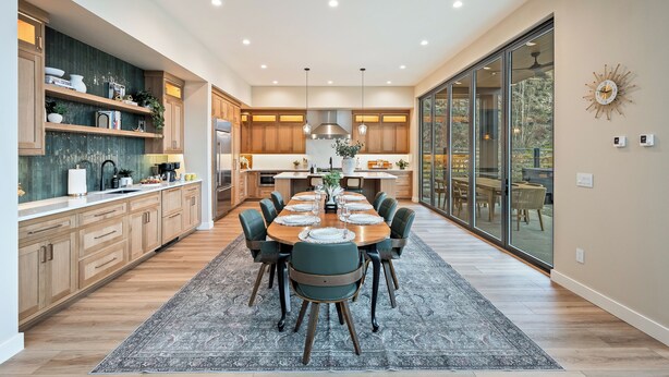 A modern kitchen with wooden cabinets, a central island, and a dining area with a large table and chairs.