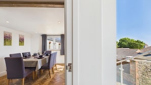 Un coin repas avec une table dressée pour quatre personnes, des chaises et une vue sur l’extérieur.